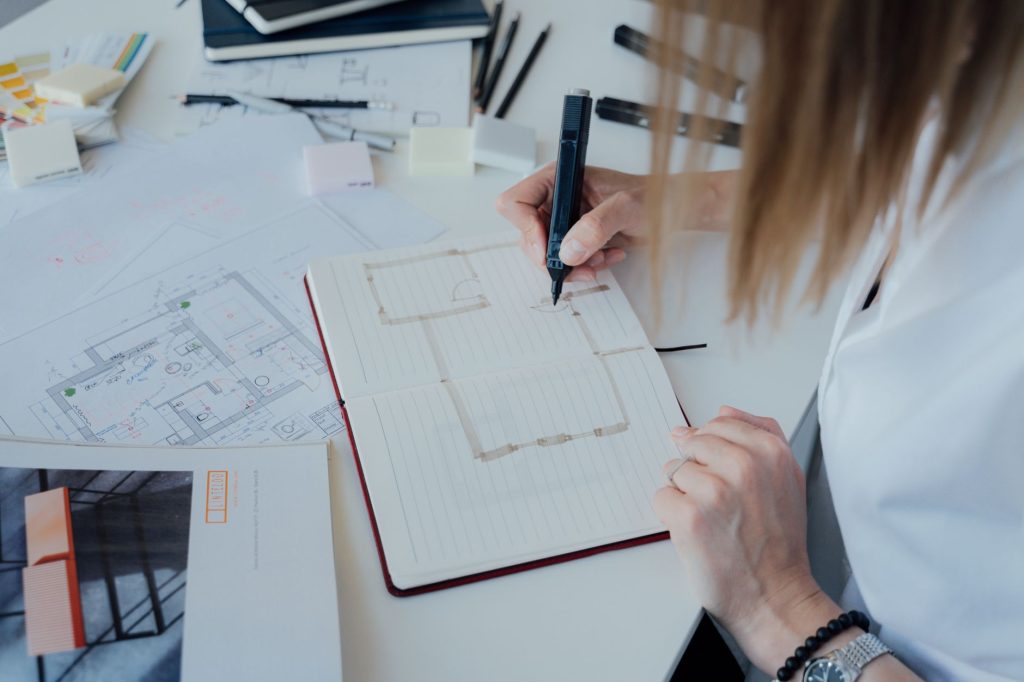 An architect sketches floor plans and designs in an organized office environment.