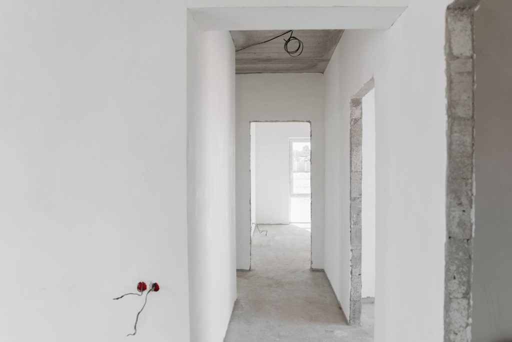 A minimalist view of an unfinished building interior with white walls and door frames.